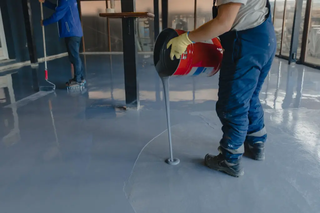Installer pouring floor coating onto a concrete floor