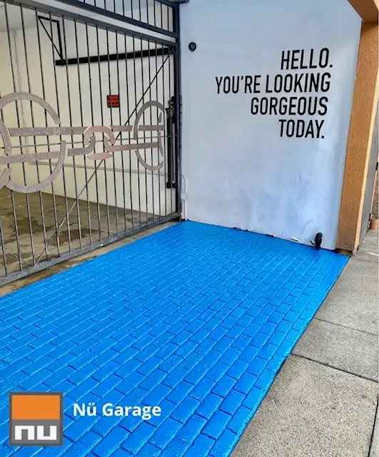 Blue garage floor coating next to a "Hello, you're looking gorgeous today" wall mural