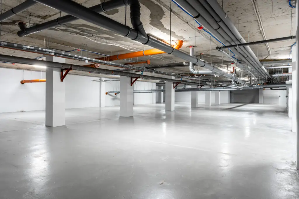 Large indoor parking area with a light gray coated concrete floor
