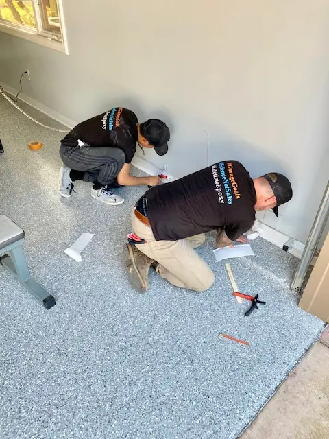 Two installers working on a gray flake epoxy garage floor