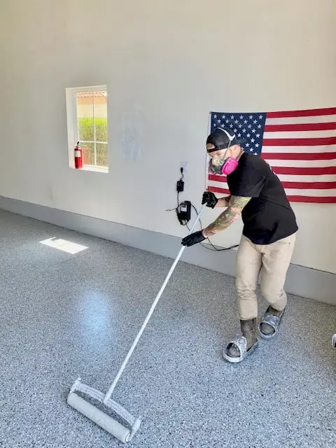 Installer spreading a flake epoxy floor coating in a garage